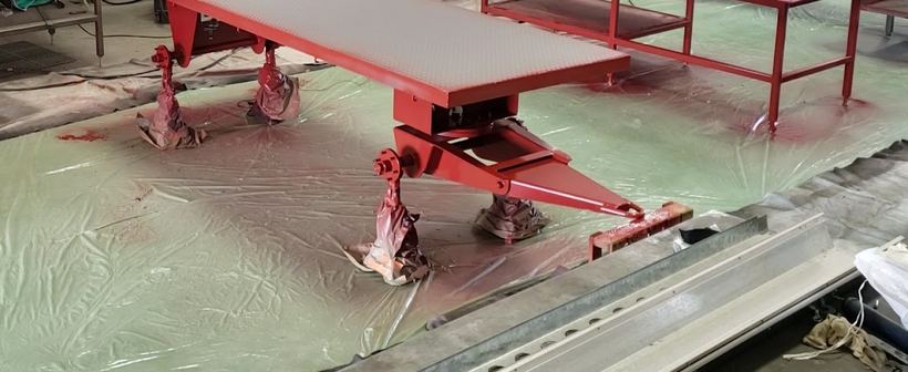 A freshly painted red steel table frame drying on drop sheets on the shop floor
